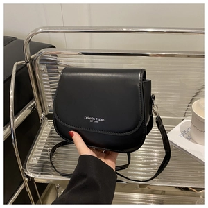 Close-up of black PU leather saddle bag with Fashion Trend white text and flap closure