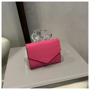 Vista dettagliata del portafoglio magenta a trama coccodrillo con elegante patta a busta