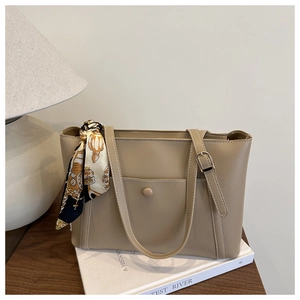 Detailed view of beige leather tote bag with white stitching and decorative silk scarf