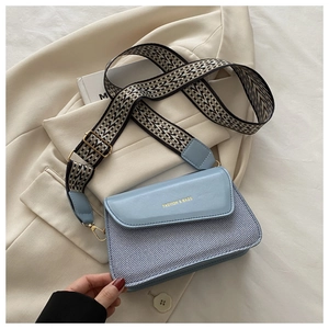 Detail of light blue crossbody bag with mixed fabric texture and geometric wide strap