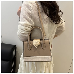 Detail of elegant khaki and white textured patchwork bag with metal buckle closure