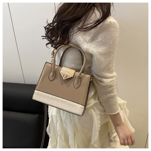 Detail of elegant two-tone faux crocodile leather handbag with secure metal clasp