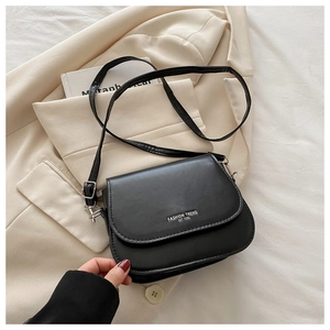 Detail view of the black flap crossbody bag with white fashion trend lettering on the cover