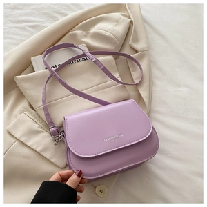 Detail of purple matte leather crossbody bag with slogan on chic beige blazer background
