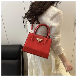 Detailed view of red leather handbag with metallic lock and crocodile pattern stitching