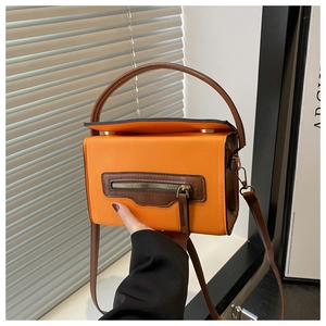 Dettaglio di una borsa quadrata color-block arancio e marrone con zip decorativa
