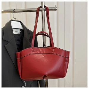 Detailed view of red leather tote bag with white contrast stitching and double handles