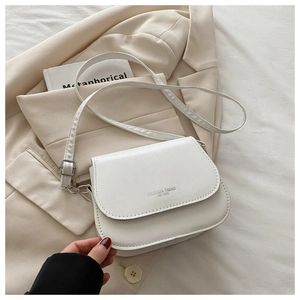 Detail of white saddle bag with Fashion Trend embossing on smooth faux leather surface
