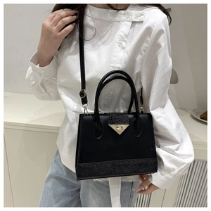 Detail of black structured crossbody bag with contrast pebble texture and gold clasp