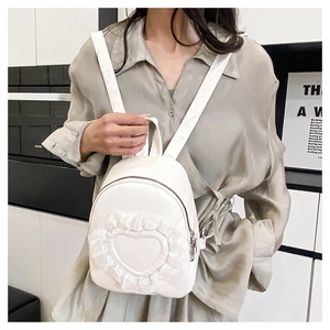 Close-up of a white mini backpack with heart lace ruffles worn by a model in casual style