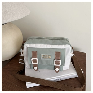 Detail of light green canvas crossbody bag with rabbit patch and brown adjustable strap