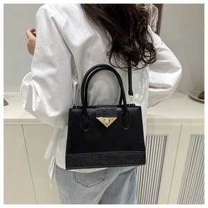 Detailed view of black patchwork shoulder bag with gold triangular lock on model