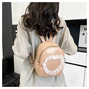 Detail of light brown PU leather backpack with heart lace appliqué shown on model back