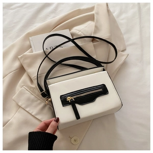 Dettaglio di una borsa a tracolla con cerniera a contrasto su un blazer beige