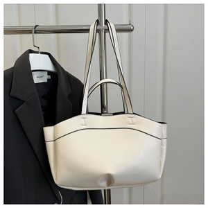 Detail of cream tote bag showing smooth leather texture and black contrast edge painting