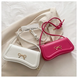 Detail of cream and magenta shoulder bags featuring golden bow and knotted strap