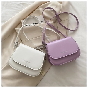 Close-up of white and lavender minimalist crossbody bags with silver stamped lettering