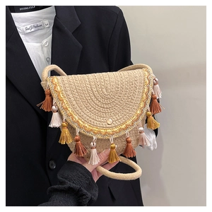 Détail d'un sac bohème en paille avec des glands colorés et des broderies métalliques chic