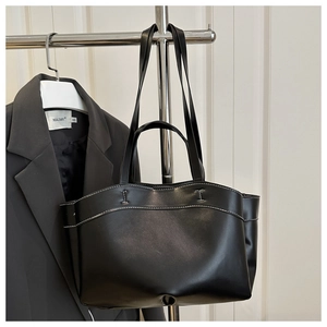 Detail of a black tote bag with white contrast stitching and long shoulder straps