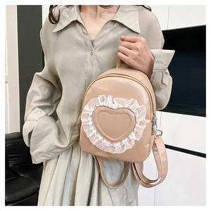 Detail of beige faux leather mini backpack featuring heart stitching and white lace trim