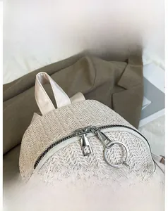 Detail view of the smooth dual metal zippers on a beige straw woven backpack