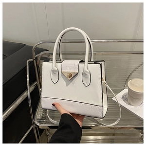 Detail of white patchwork handbag with crocodile texture and metal triangular buckle lock