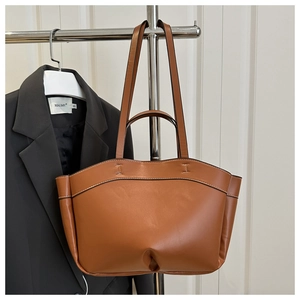 Detail of a brown leather tote bag showing smooth texture and decorative stitching design