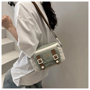 Detail of canvas crossbody bag with green contrast flap and adjustable brown strap
