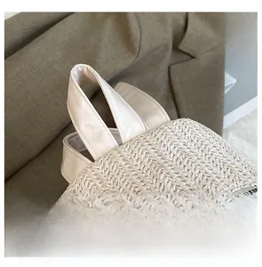 Close-up of woven straw texture with faux leather handles and metal zippers on beach bag