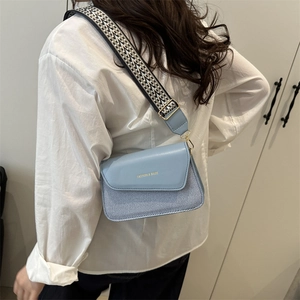 Light blue crossbody bag with striped panel and patterned wide shoulder strap for women