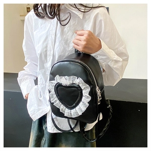Detail of black mini backpack with lace heart pocket and silver zippers on a model
