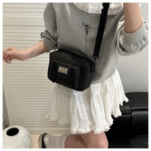 Detail of black canvas crossbody bag with dual buckles and fashion lovely logo patch