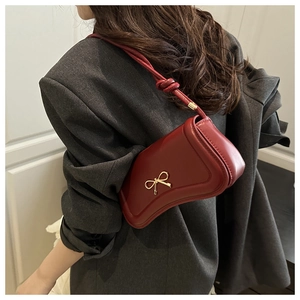 Close-up of wine red irregular shaped handbag with gold bow and elegant knot strap