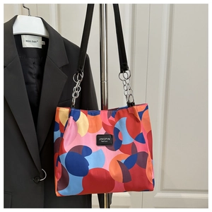 Detail of colorful geometric pattern tote bag with leather tag and chain strap