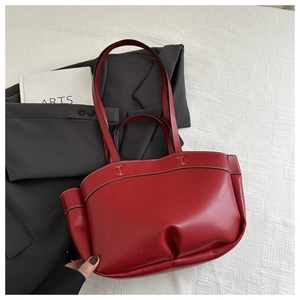 Detail of red tote bag featuring contrast white stitching and spacious side fold design