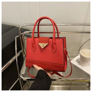 Detail of red textured leather handbag with gold triangle lock on acrylic stand