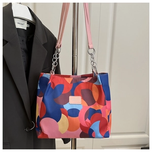 Detail of colorful geometric pattern tote bag with pink leather strap and metal chain