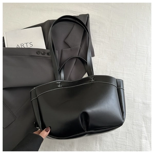 Detail of matte black tote bag with white contrast stitching and long shoulder straps