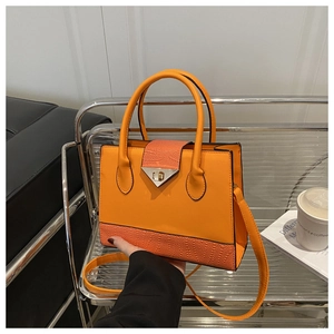 Close-up of orange textured handbag with snake skin panel and silver triangle lock