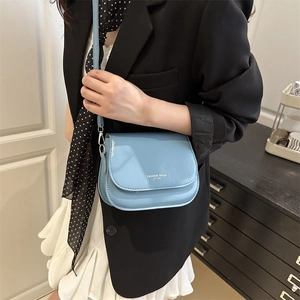 Stylish light blue saddle bag with adjustable shoulder strap worn with black blazer