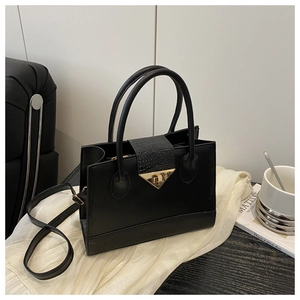 Detail of multi-textured black leather bag with gold triangular lock and crossbody strap