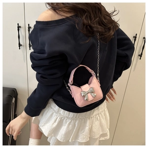 Gros plan d'un mini sac à bandoulière rose avec un grand nœud en métal argenté
