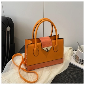 Detailed view of the vibrant orange handbag featuring a gold triangle twist lock and texture
