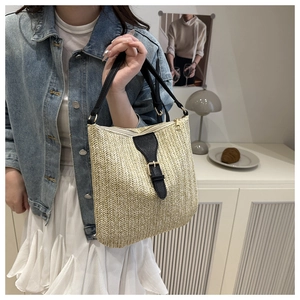 Detail showing woven straw texture and black leather strap of the summer shoulder bag