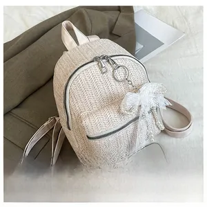 Mini straw woven backpack with lace bow and bead detail shown next to a smartphone