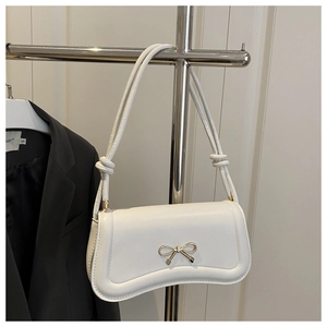 Detail of white ivory bag featuring a golden metal bow buckle and knot strap design