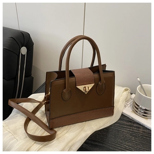 Detail of vintage brown textured leather handbag with gold twist lock and dual handles