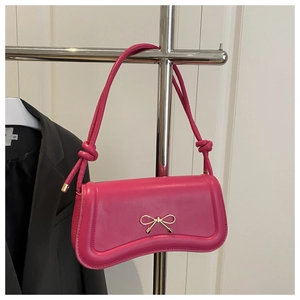 Detail of rose pink baguette bag with golden bow clasp and knotted strap design
