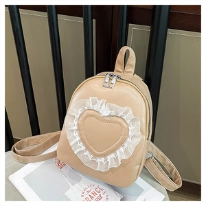 Detail of beige mini backpack featuring heart-shaped leather patch with white lace trim