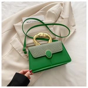 Close-up of modern gold metal handle and green textured leather on a crossbody bag